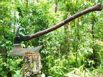Decorative axe with a wooden handle on a green leafy background